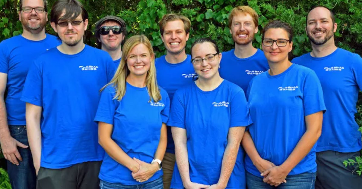 Group of males and females standing in front of greenery all wearing royal blue shurts